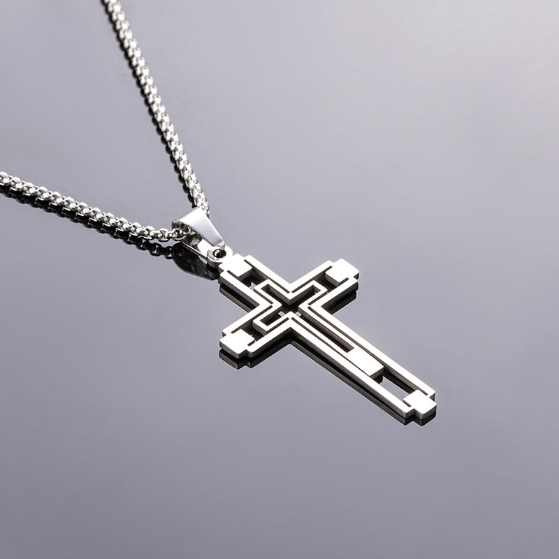 Silver cross pendant on a chain against a gray background