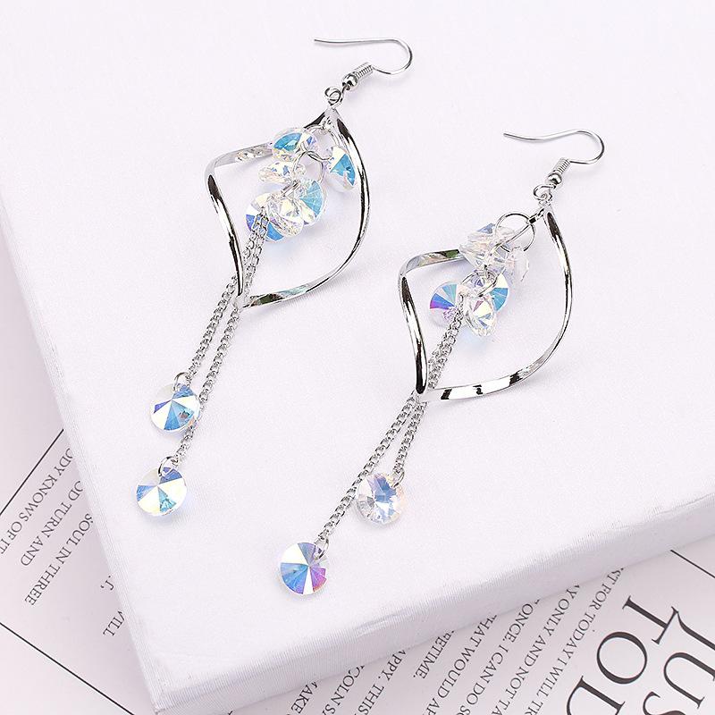 Silver earrings with crystal-like stones on a newspaper background