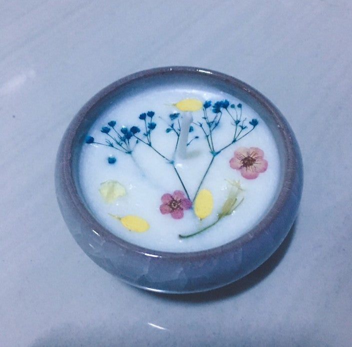 Candle with floral design in a glass container on a white surface