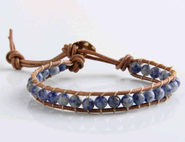 Bracelet with blue beads and brown leather strap on a white background