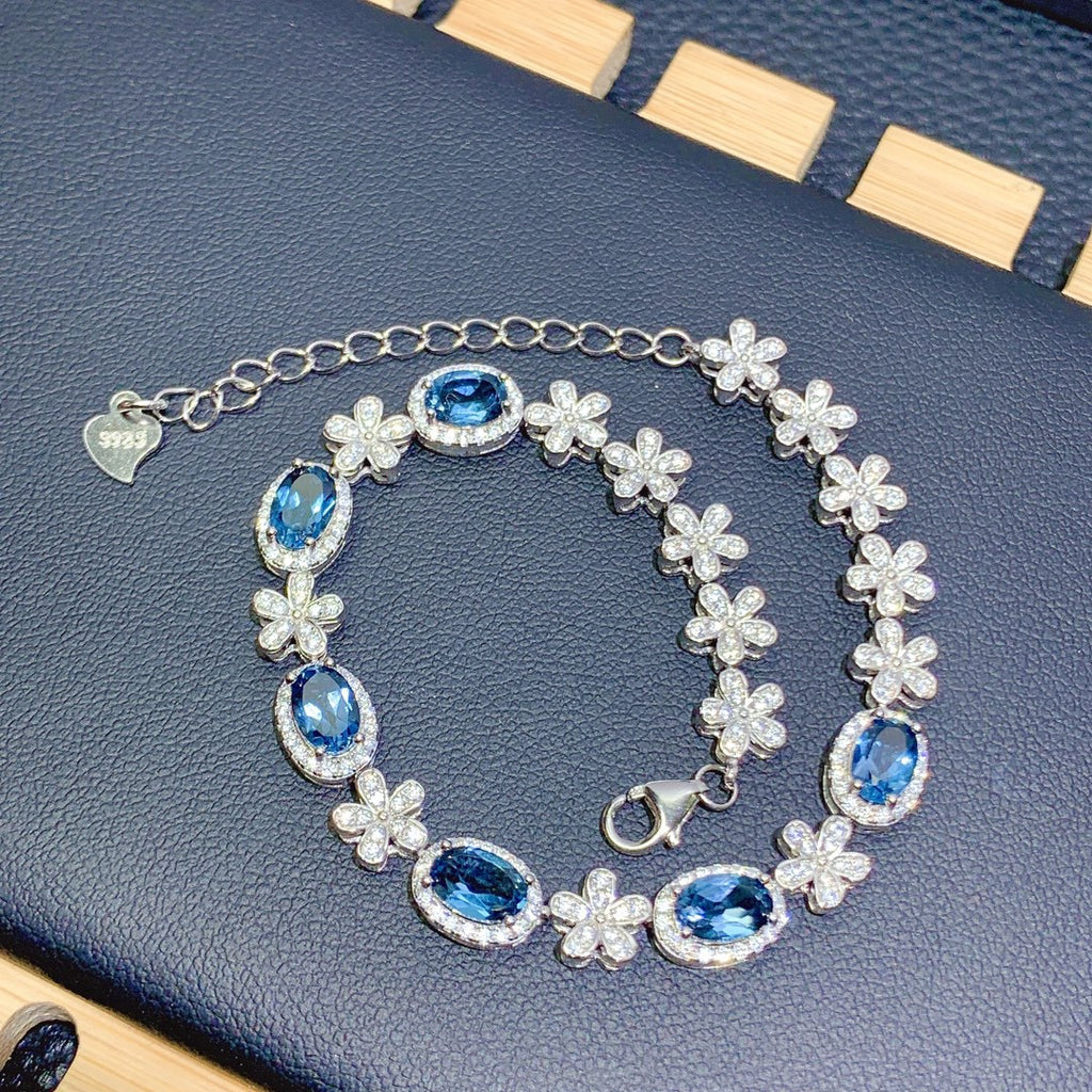 Silver bracelet with blue gemstones on a dark surface