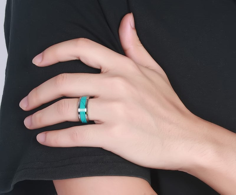 Hand wearing a turquoise ring on a black background