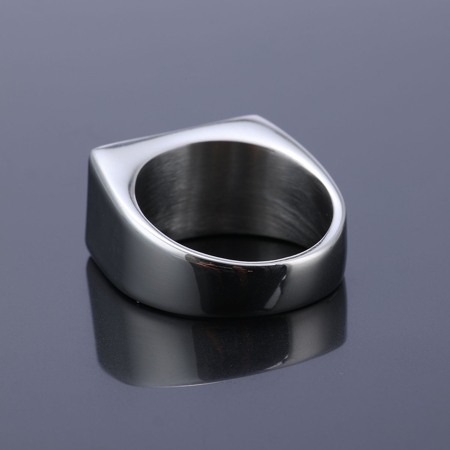 Silver ring on a reflective purple surface with a gradient background