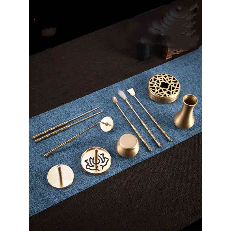 Set of gold tea accessories on a blue mat with a dark background
