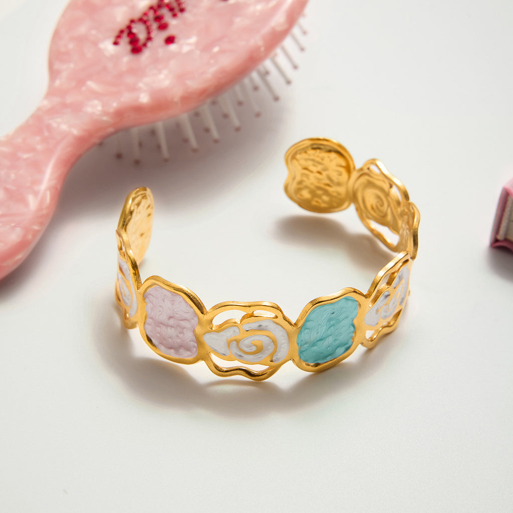 Gold bracelet with floral designs on a light background