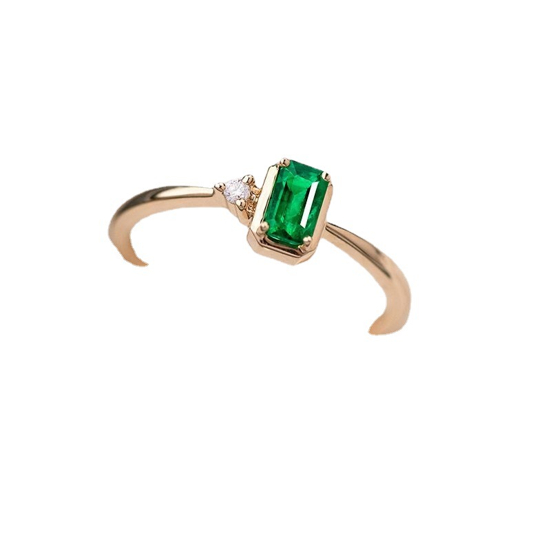 Gold ring with a green gemstone and small diamond on a white background
