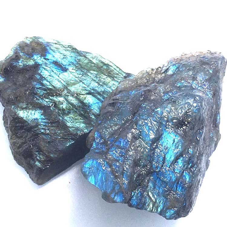 Two rough labradorite stones on a white background