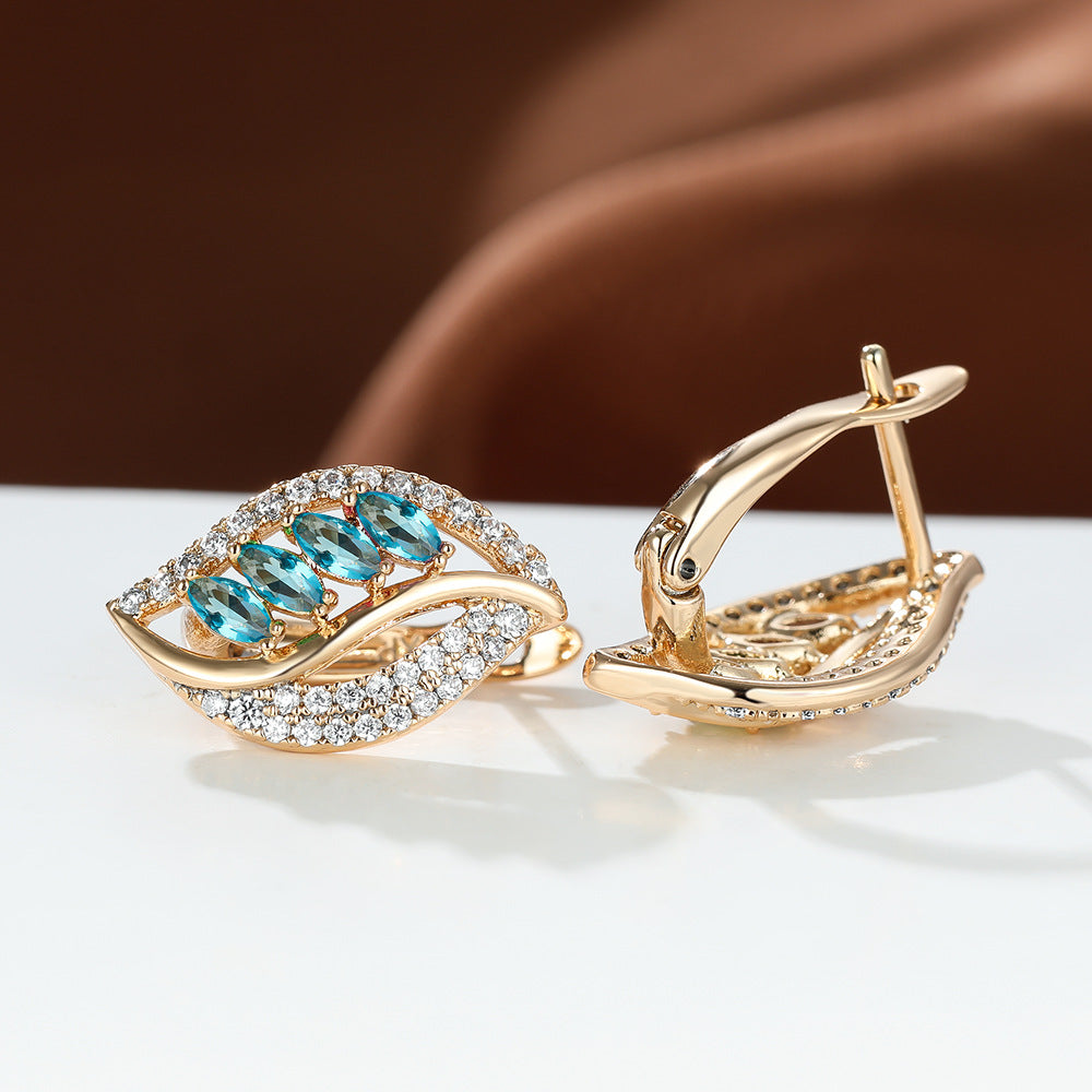 Gold earrings with blue gemstones on a white surface