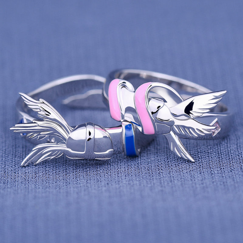 Silver bird-shaped ring with pink and blue accents on a blue fabric background