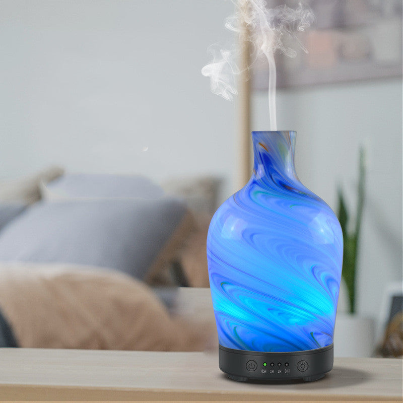 Blue marbled diffuser emitting mist on a wooden surface with a blurred background