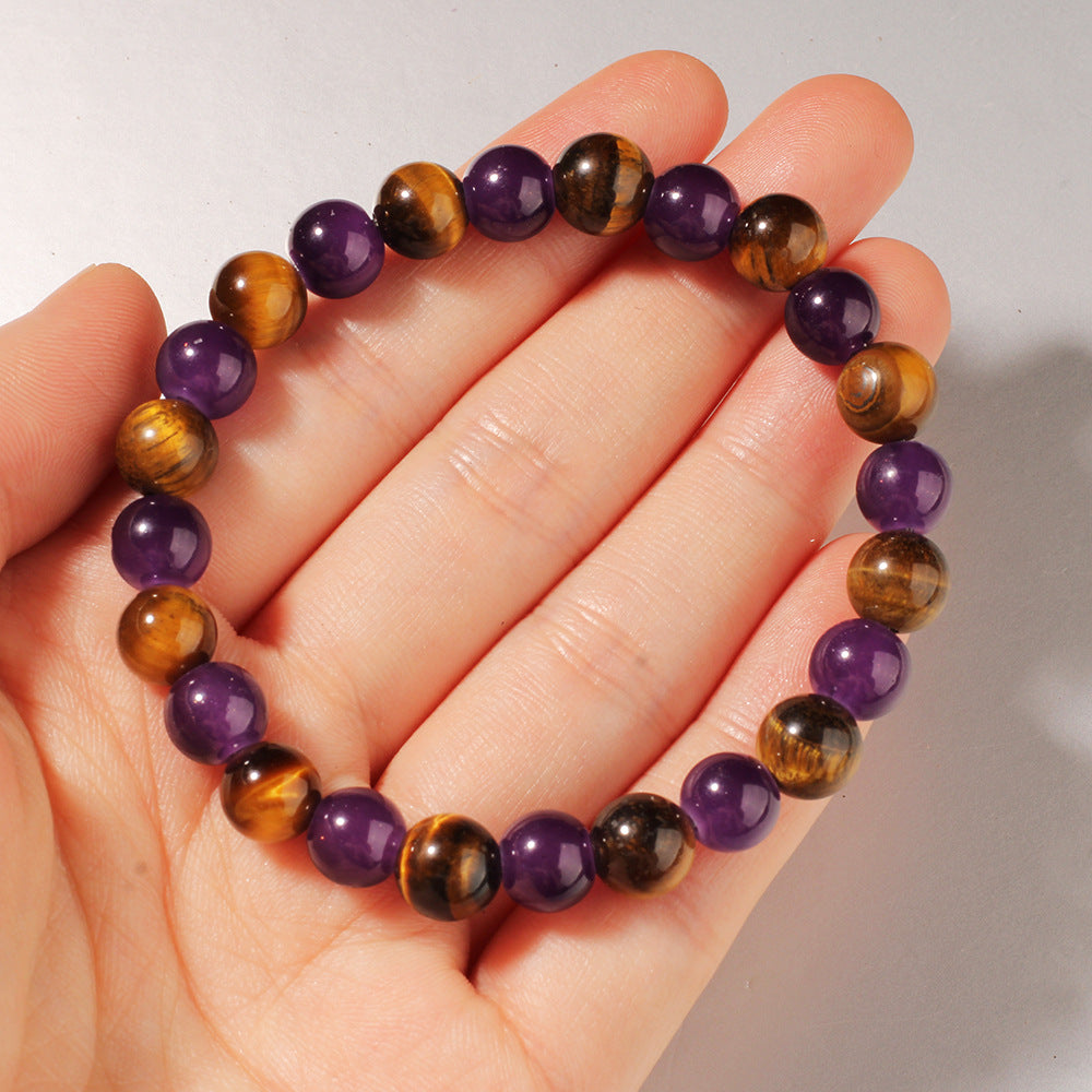 Beaded bracelet with purple and brown beads on a hand against a neutral background