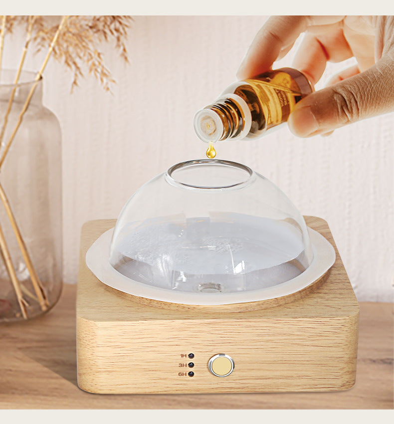Person pouring oil into a diffuser on a wooden surface with a blurred background