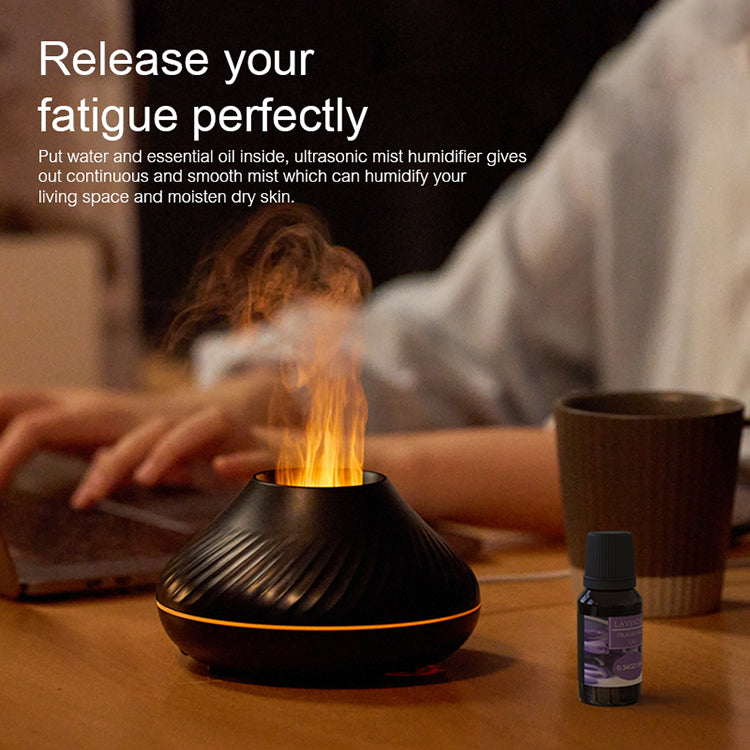 Ultrasonic mist humidifier with flames on a table next to a bottle of essential oil.