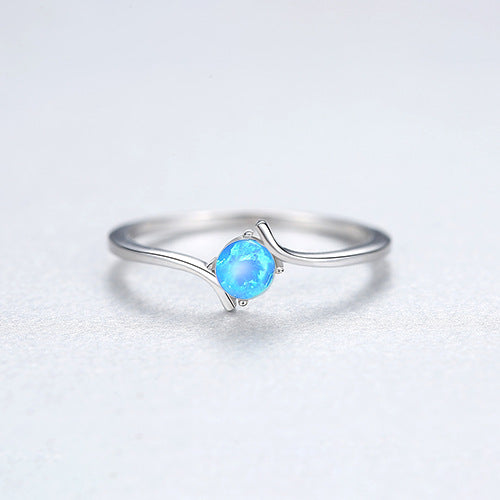 Silver ring with a blue gemstone on a light gray background