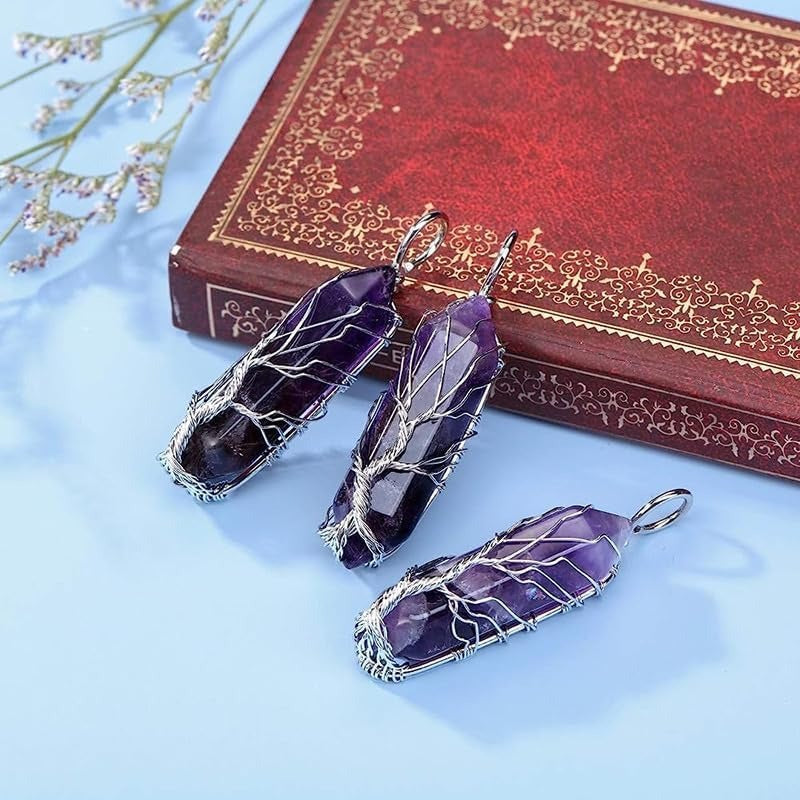 Three purple crystal pendants on a light blue surface with an ornate red book in the background.