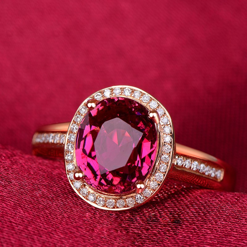 Ring with a pink gemstone and rose gold band on a red background