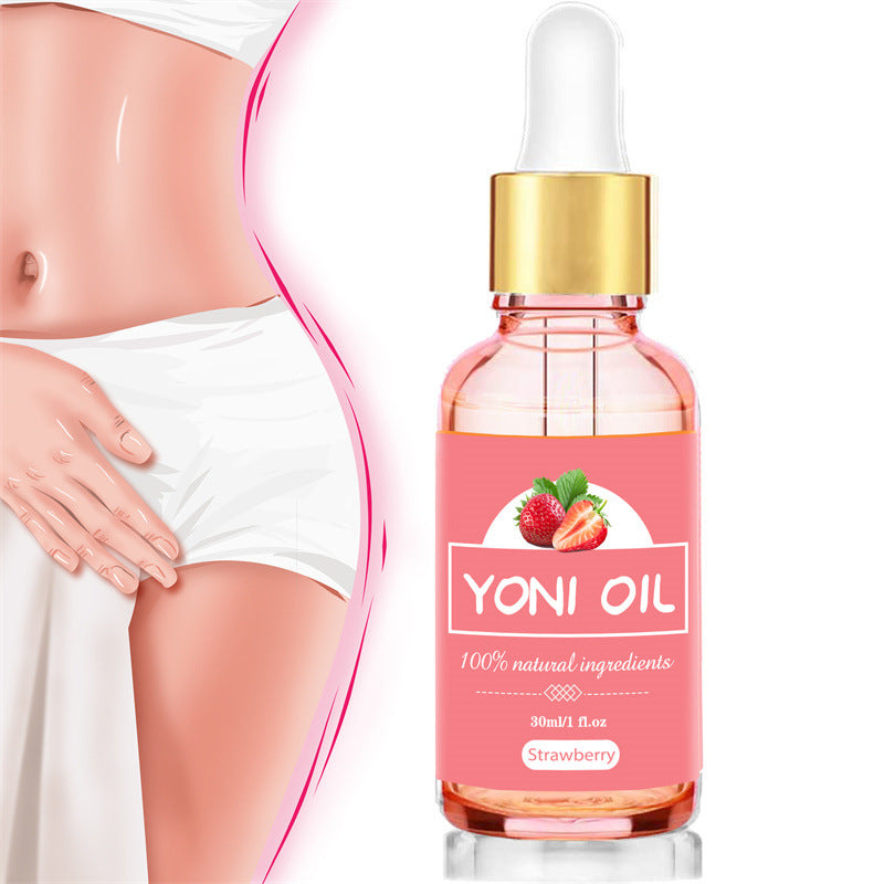 Yoni oil bottle with strawberry flavor next to a woman's abdomen on a white background