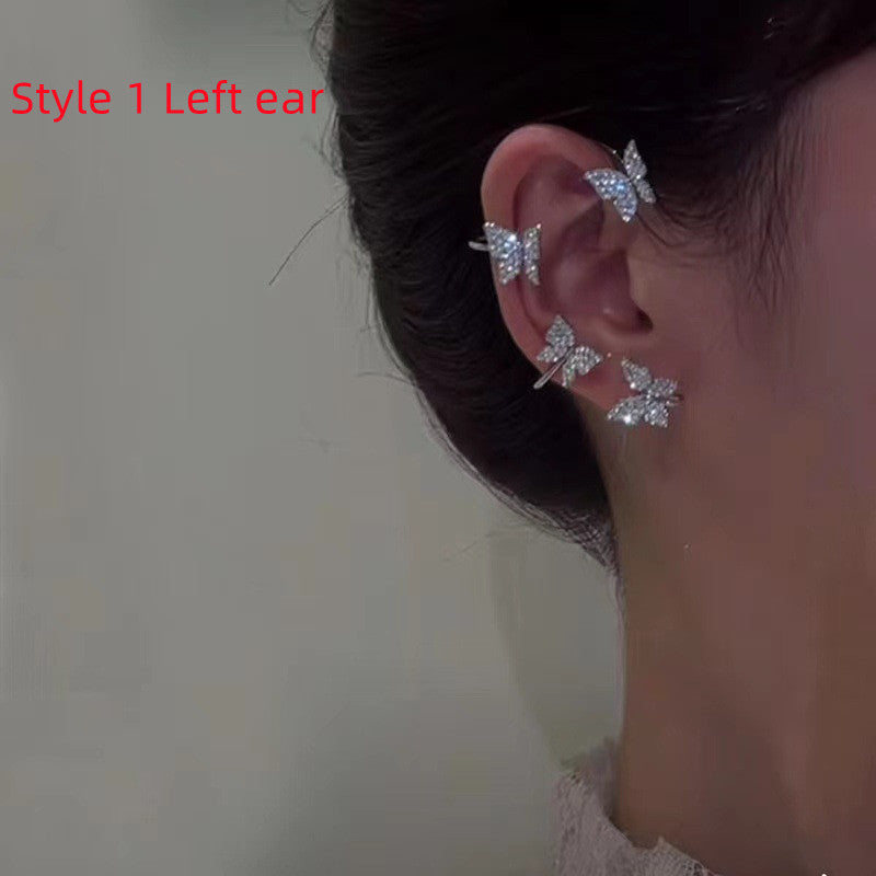 Close-up of an ear wearing a butterfly-shaped earring with a blurred background.