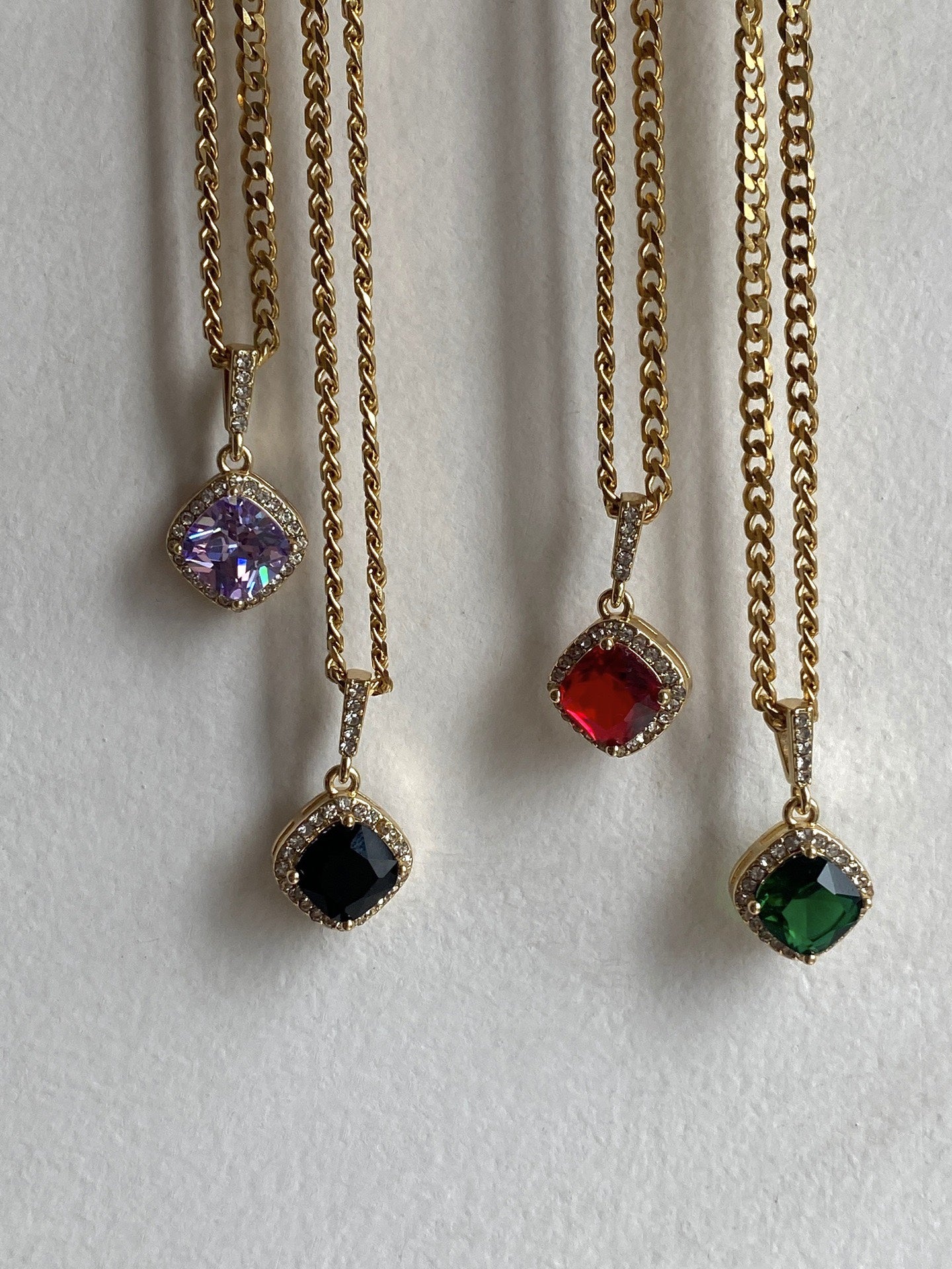 Four gold necklaces with colored gemstones on a white background