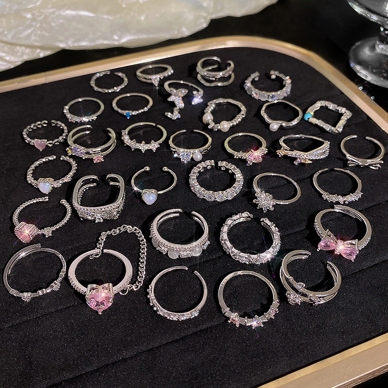 Collection of silver hoop earrings with pink gemstones on a black tray.