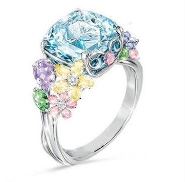 Ring with a large blue gemstone and smaller pastel-colored stones on a white background