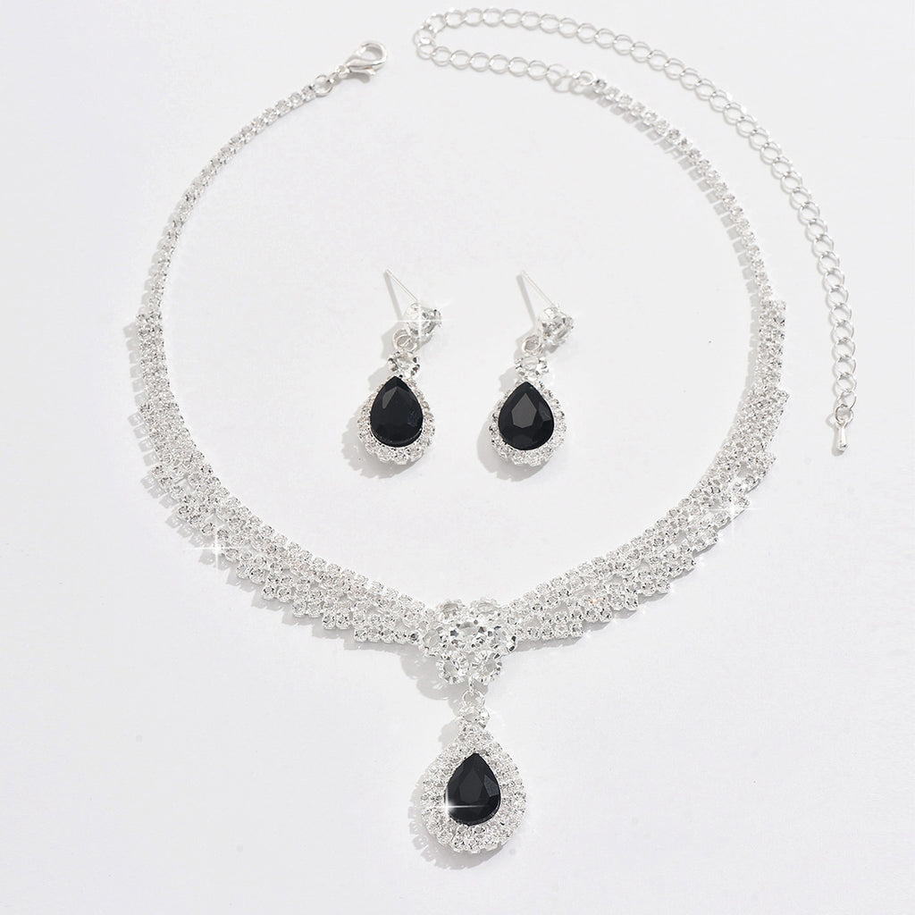 Jewelry set with necklace and earrings featuring black teardrop stones on a white background