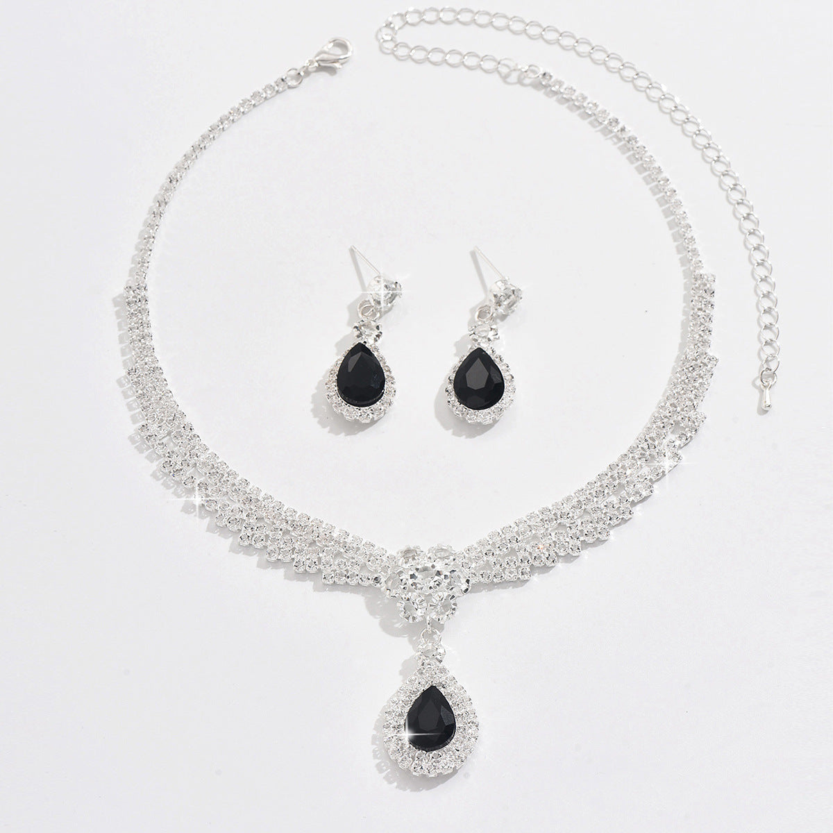 Jewelry set with necklace and earrings featuring black teardrop stones on a white background