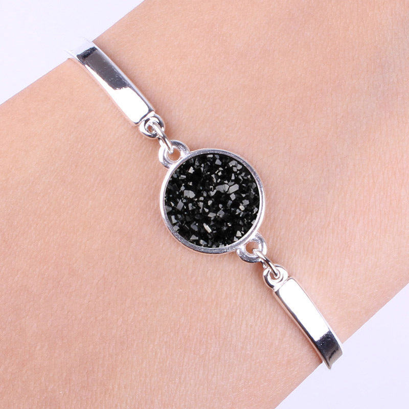 Silver bracelet with a black druzy stone on a wrist against a white background