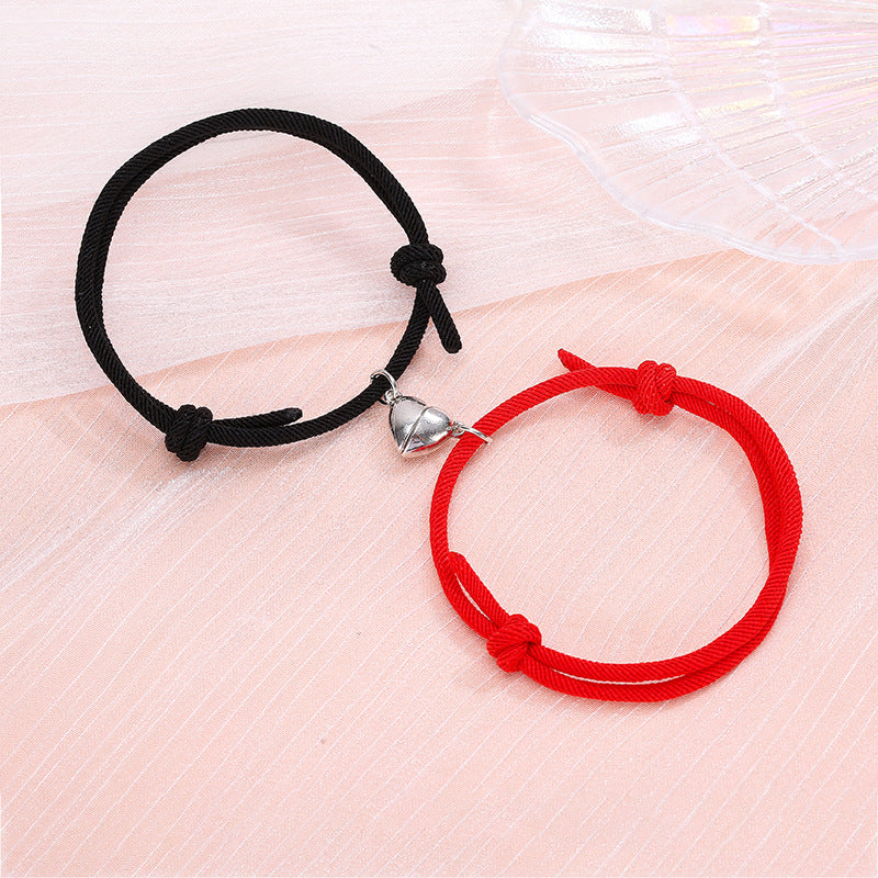 Black and red bracelets with heart-shaped charms on a light pink surface