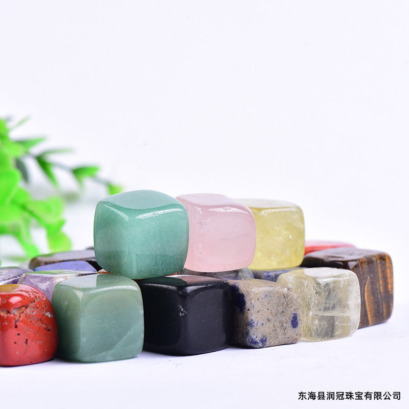 Colorful gemstones stacked on a white surface with a blurred green plant in the background