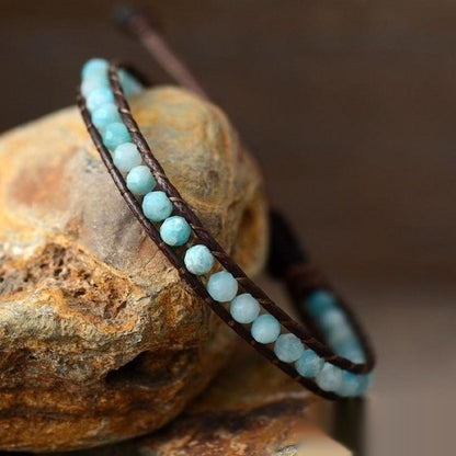 Bracelet with turquoise beads on a brown leather strap on a stone surface
