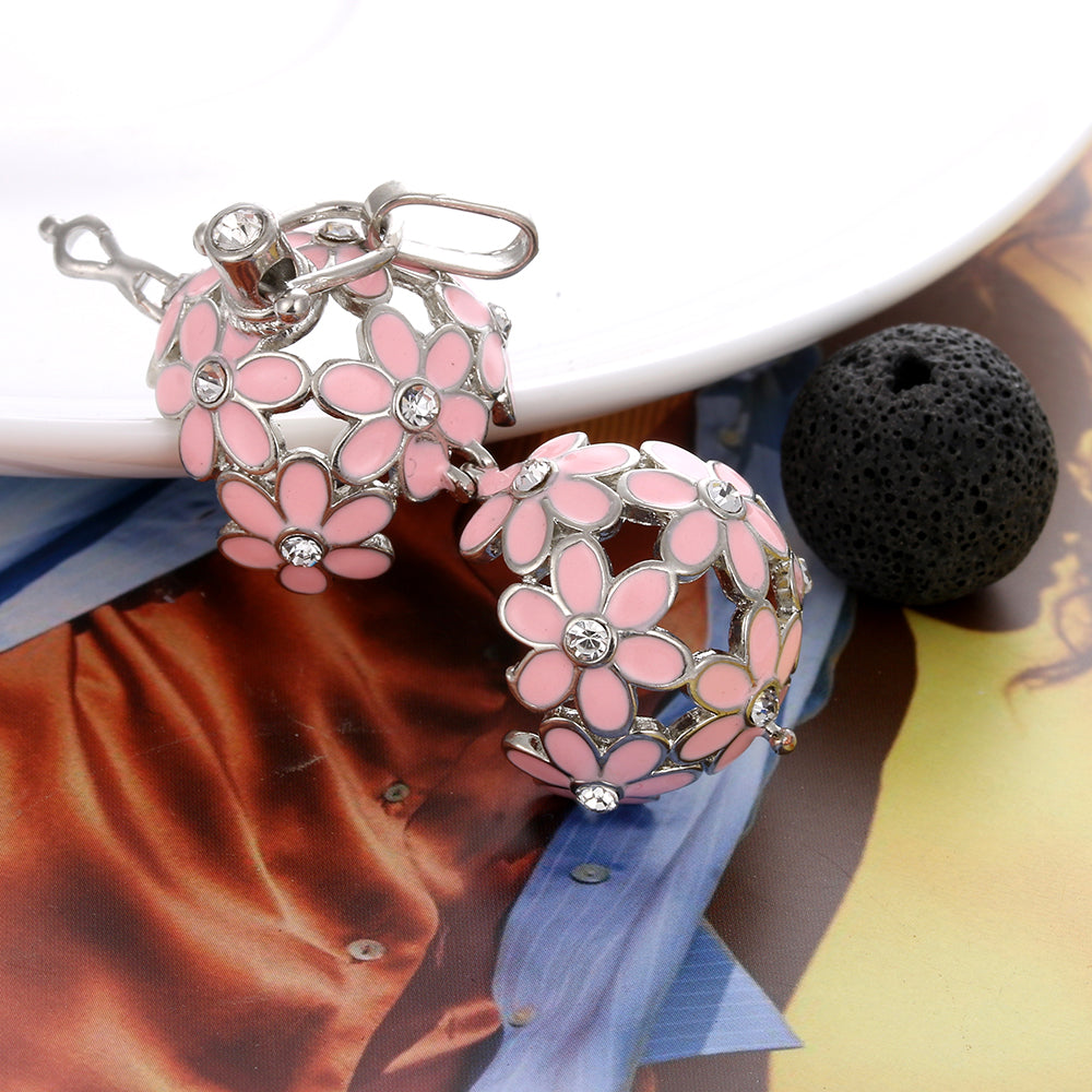 Pink flower-shaped keychains with silver accents on a textured surface.