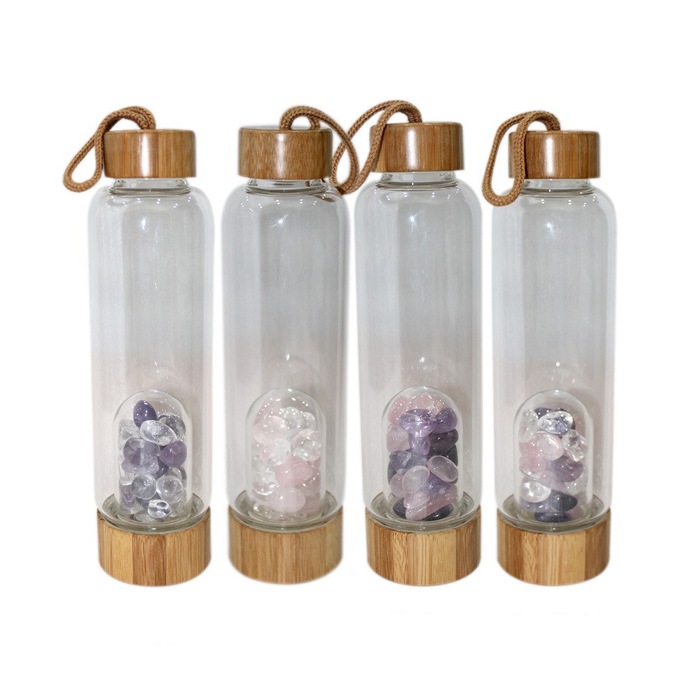 Four transparent water bottles with wooden lids and bases, containing colorful stones.