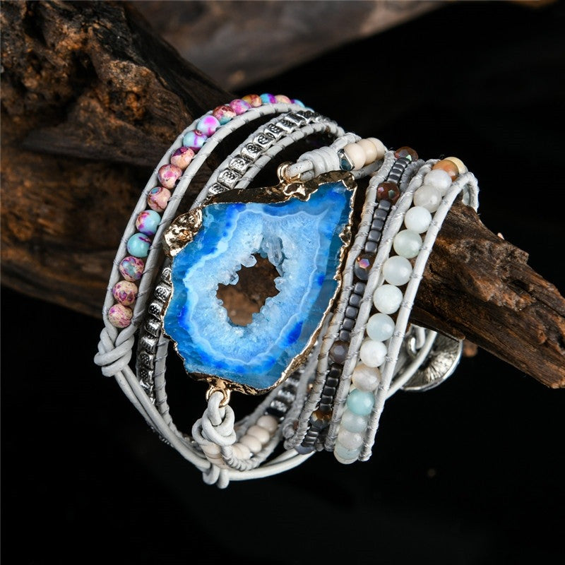 Multistrand bracelet with a blue geode centerpiece on a dark background