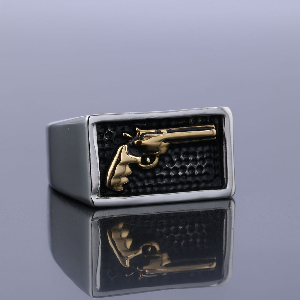Ring with gold gun emblem on a reflective surface