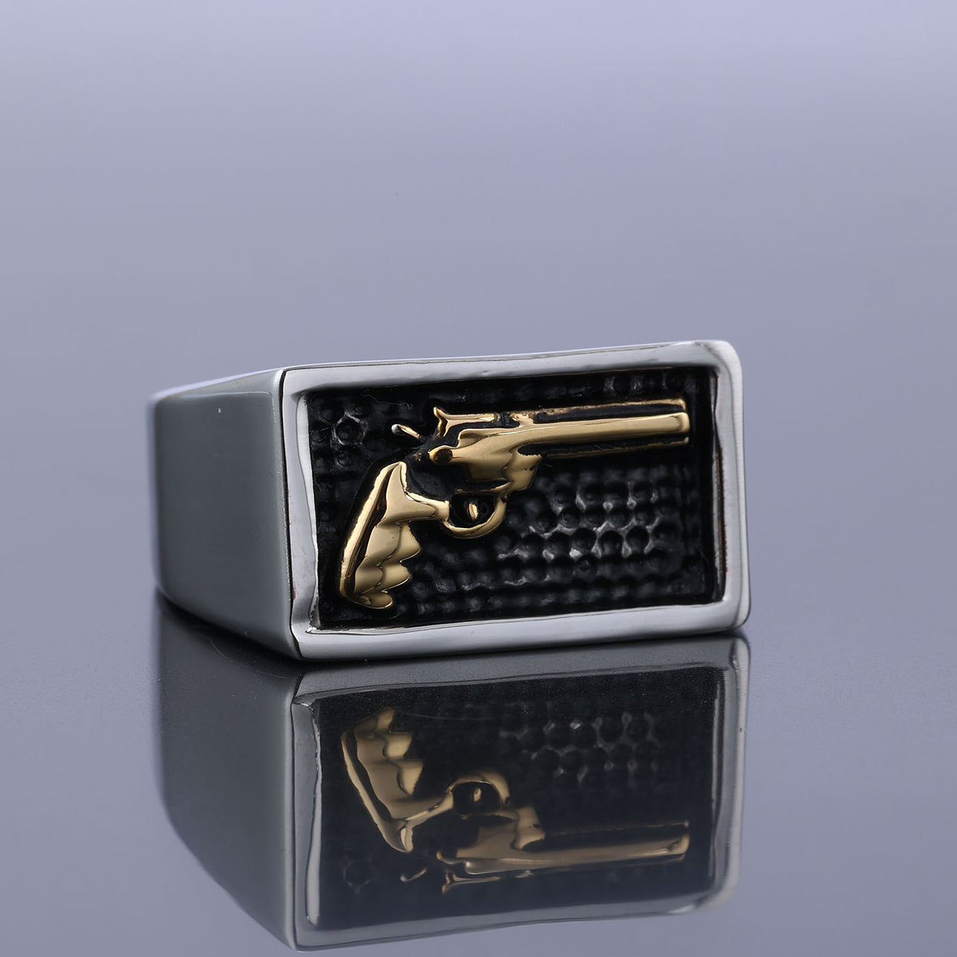 Ring with gold gun emblem on a reflective surface