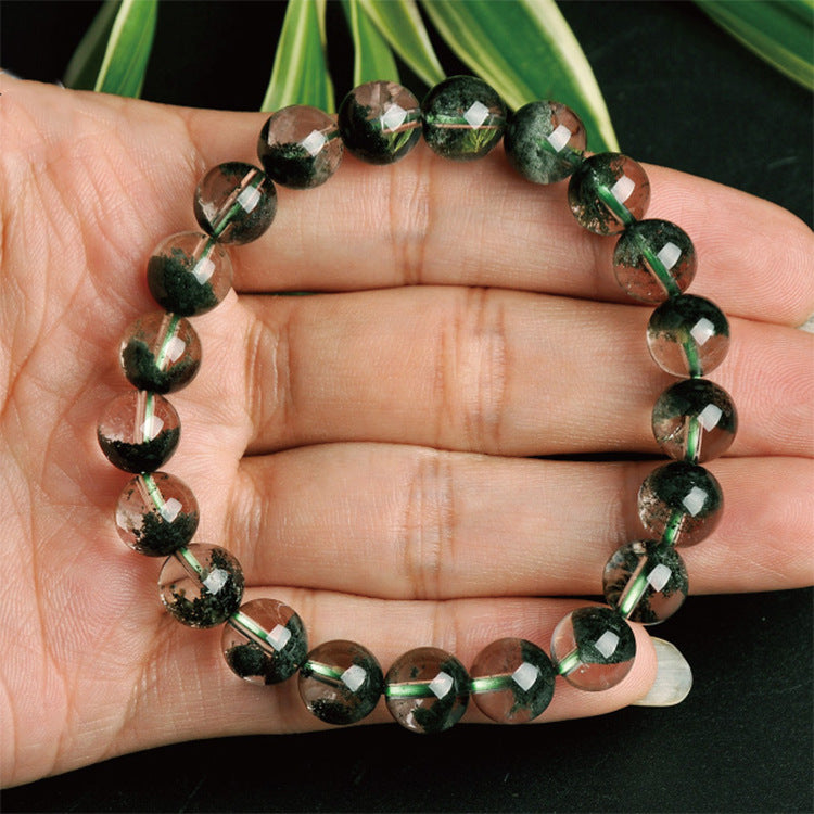 Green beaded bracelet on a hand with a dark background
