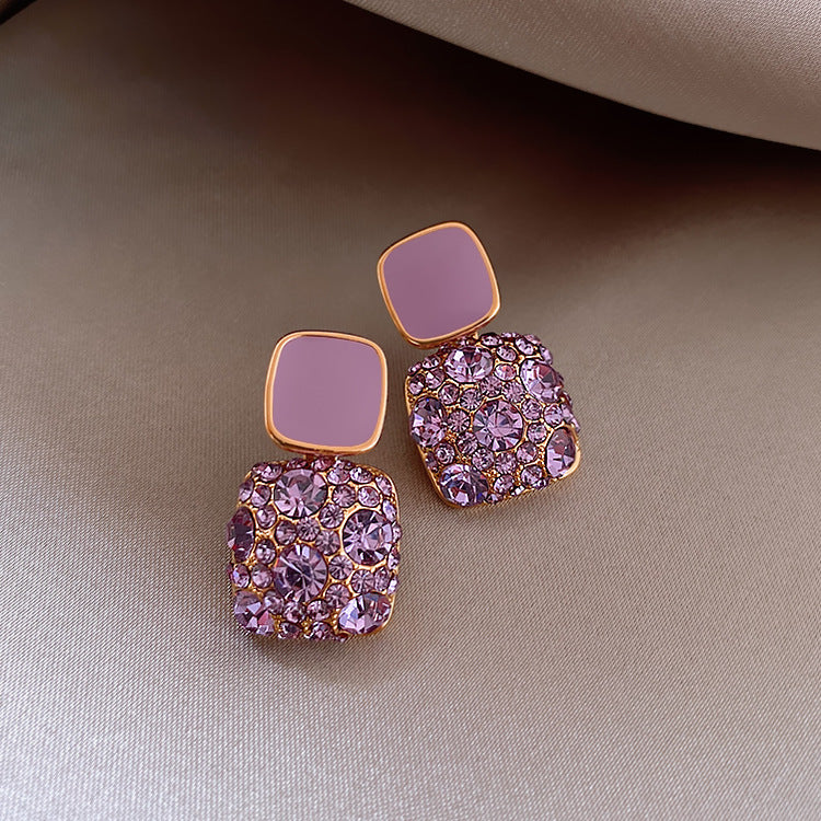 Pair of pink and gold earrings on a beige fabric background