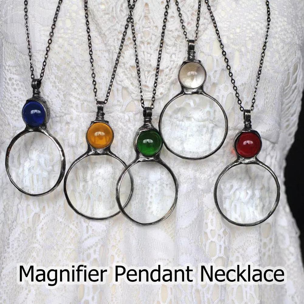 Five magnifier pendant necklaces with colored stones on a textured white background.