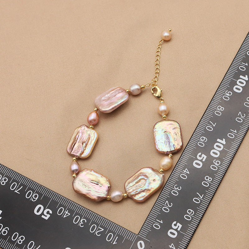 Necklace with pink and gold beads on a beige background with a ruler for scale.