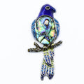 Colorful bird-shaped brooch with abalone shell center on a white background