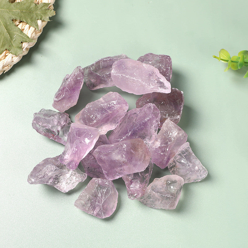 Raw amethyst crystals on a light green background with leaves.