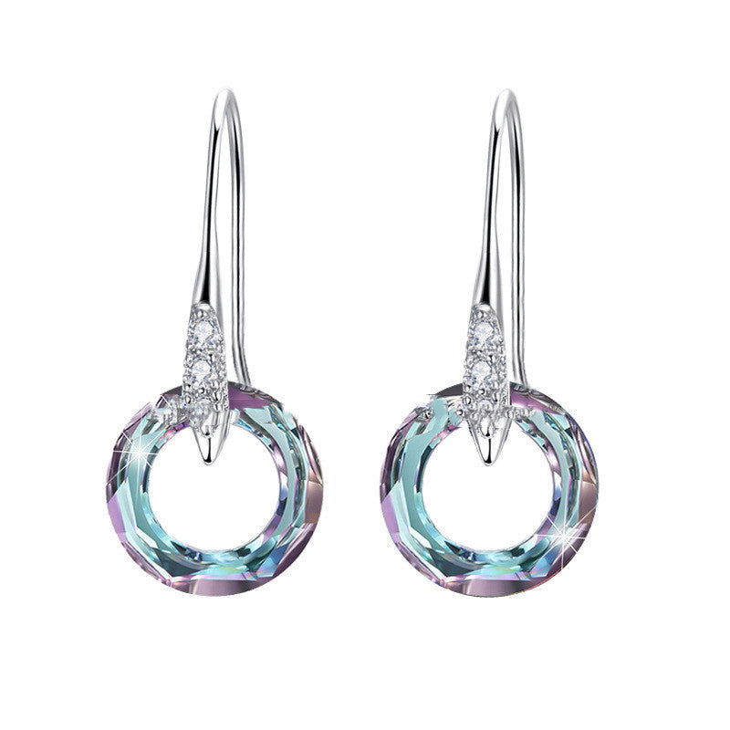 Pair of earrings with circular design and gemstones on a white background