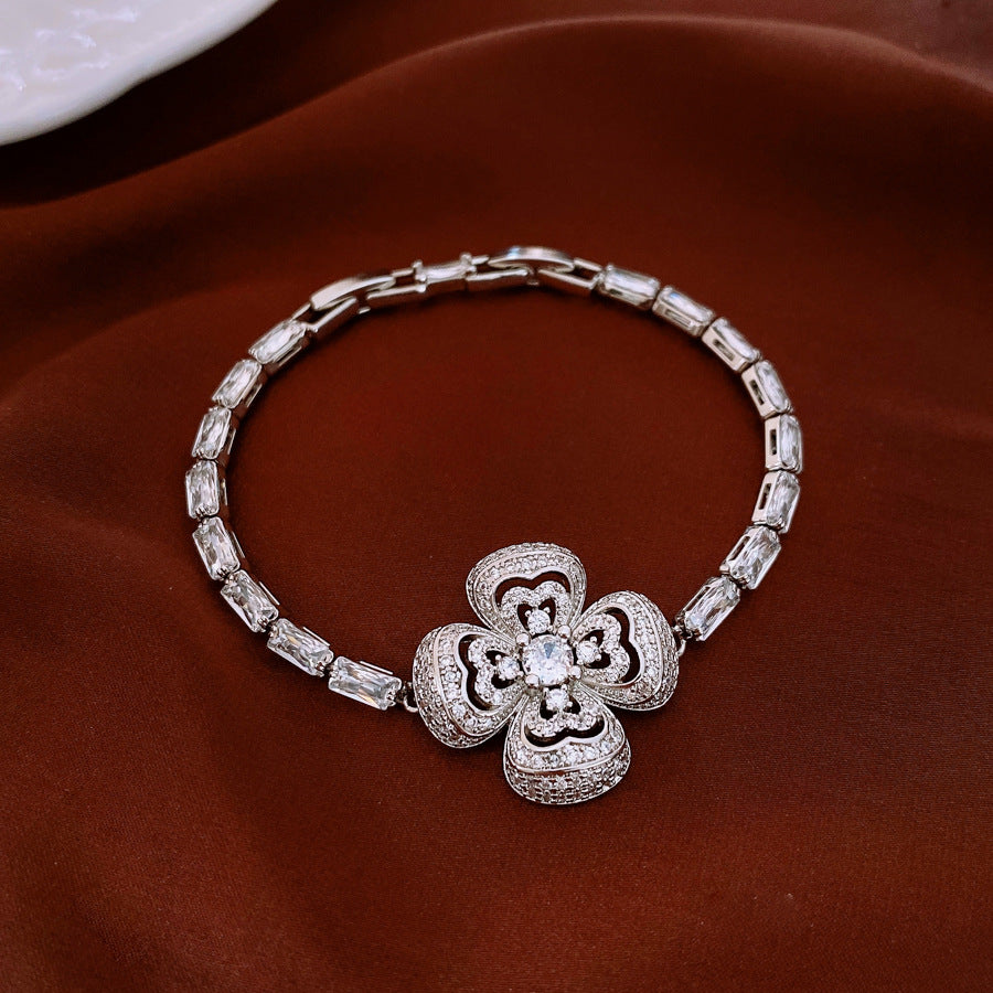 Silver bracelet with a floral clasp on a brown surface