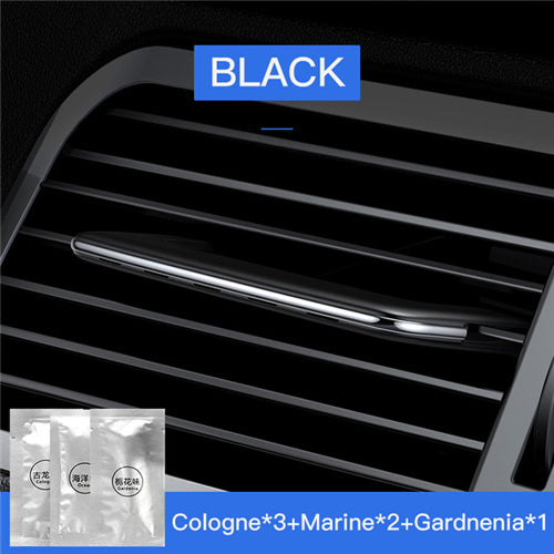 Car air vent with black trim and a small sample of cologne packaging.