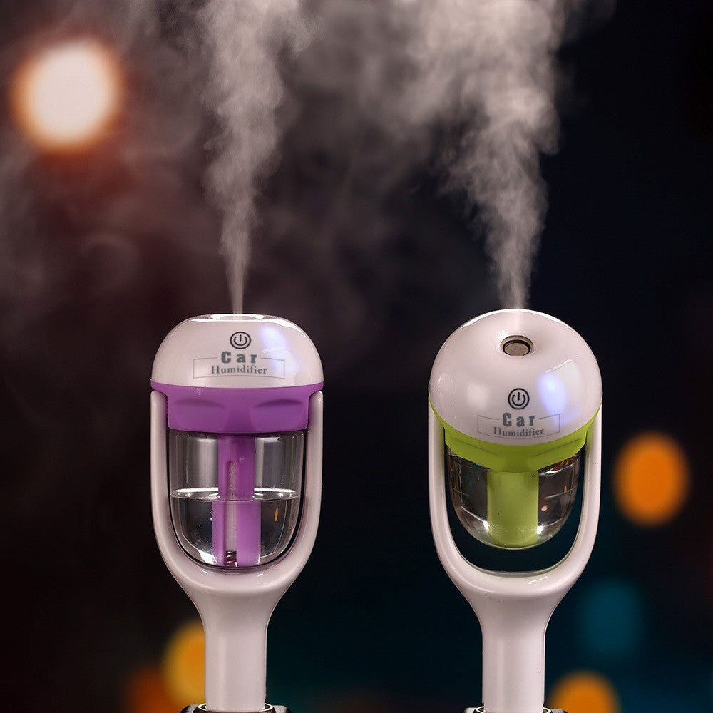 Two car humidifiers with steam emitting against a dark background with colorful lights.