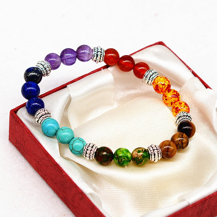 Multicolored beaded bracelet with silver accents on a white pillow inside a red box.
