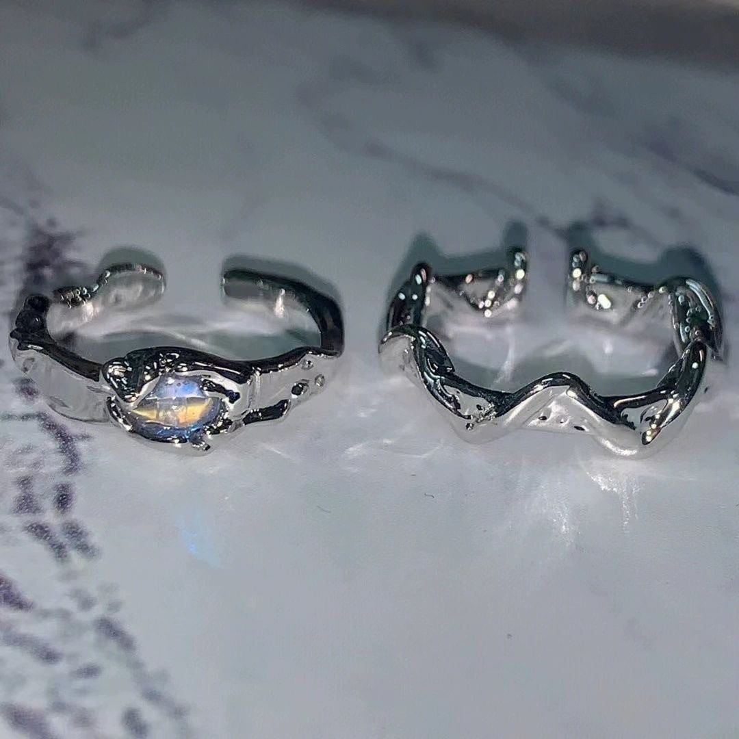 Two silver rings with intricate designs on a textured surface