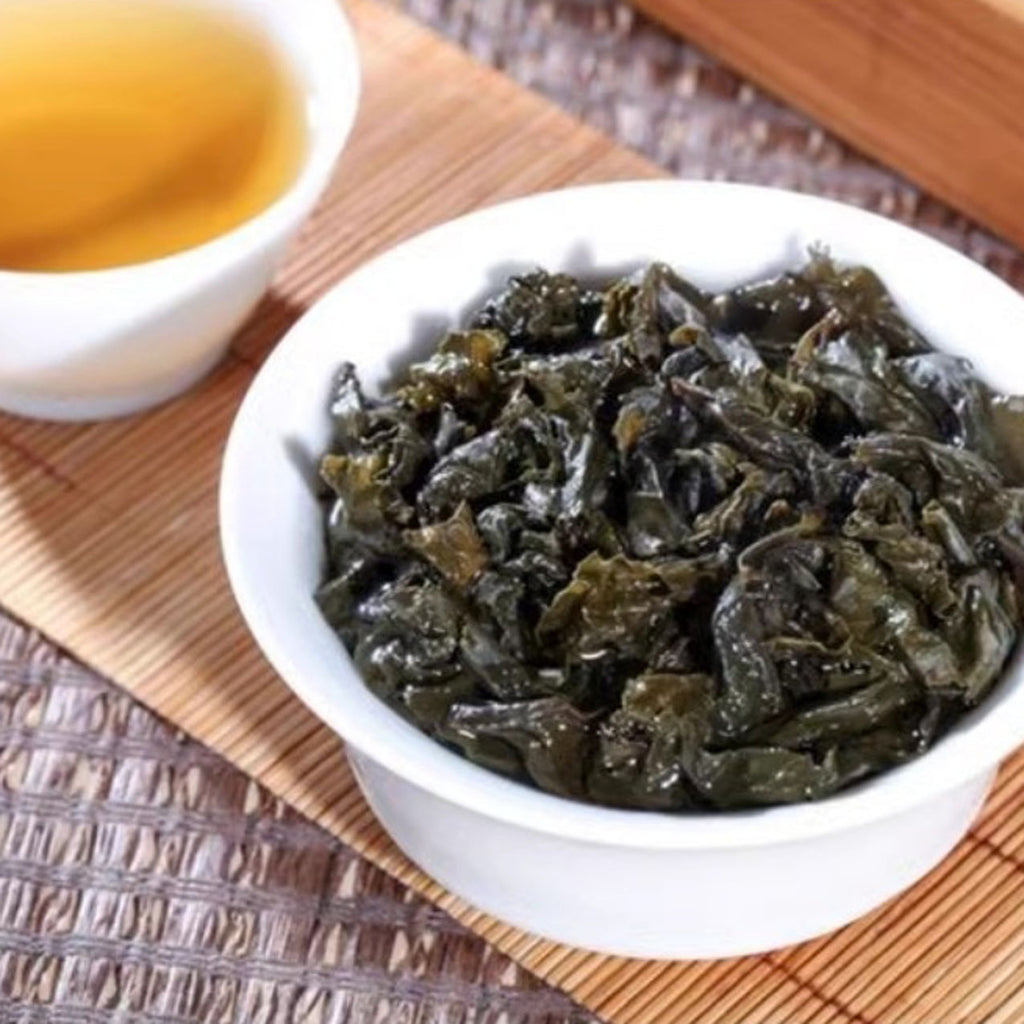 Dried seaweed in a white bowl on a wooden surface with a small cup of tea.