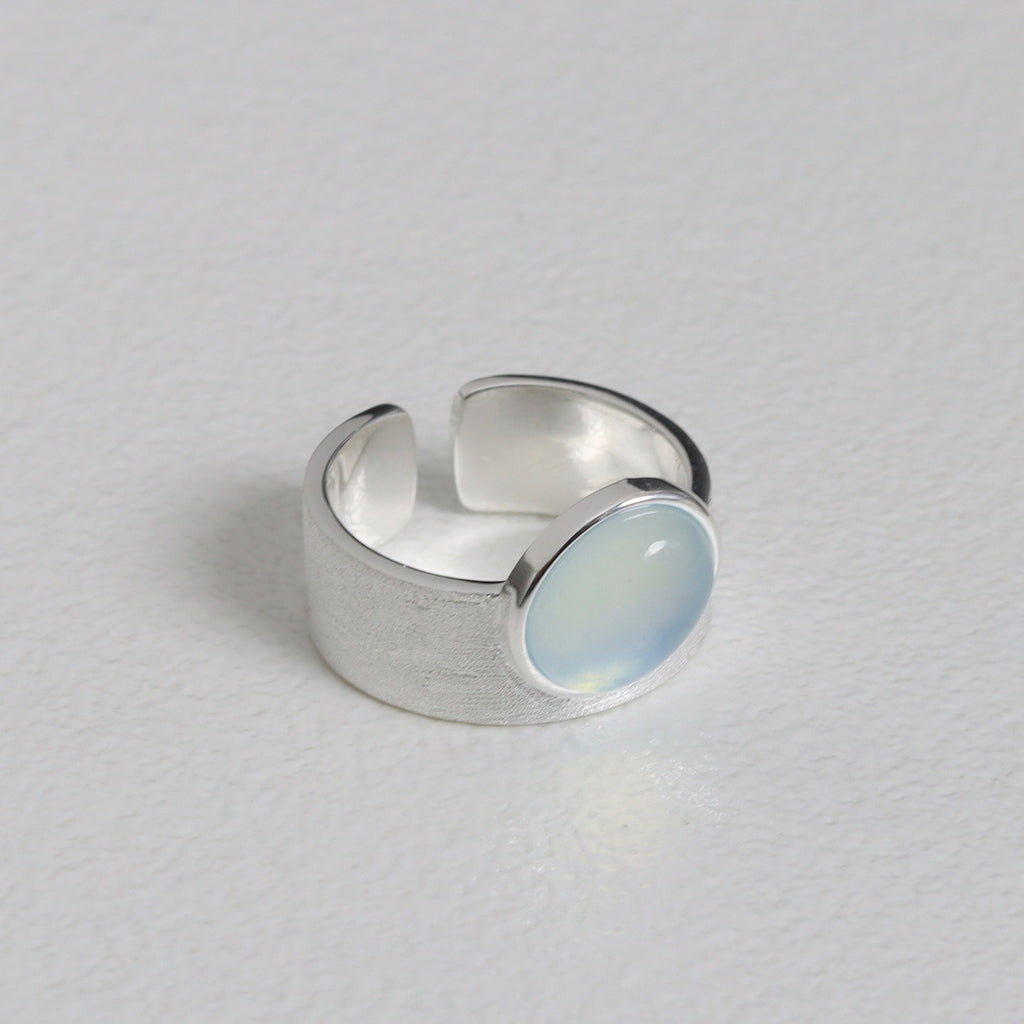 Silver ring with a light blue stone on a gray background